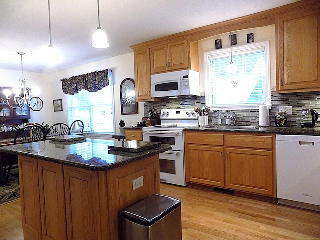 kitchen featuring white appliances, a kitchen island, an inviting chandelier, sink, and hanging light fixtures