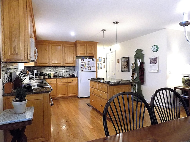 kitchen with pendant lighting, light hardwood / wood-style flooring, tasteful backsplash, and white appliances