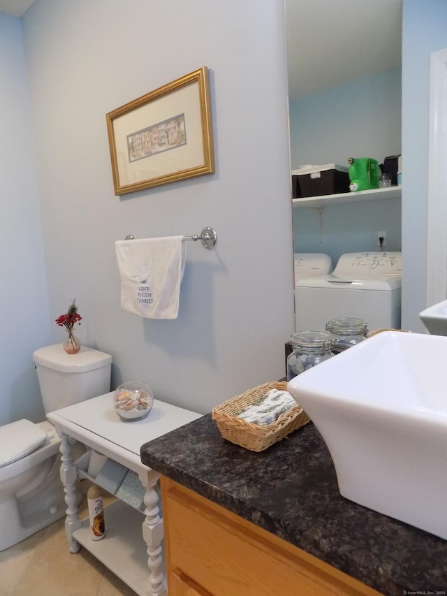 bathroom with toilet, separate washer and dryer, tile patterned flooring, and sink