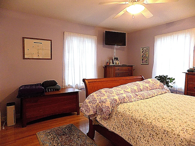 bedroom with ceiling fan, multiple windows, and hardwood / wood-style flooring