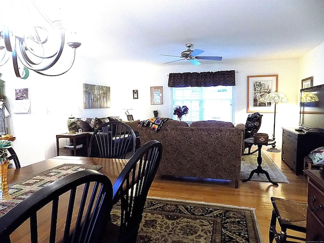 dining space featuring light wood-type flooring and ceiling fan with notable chandelier