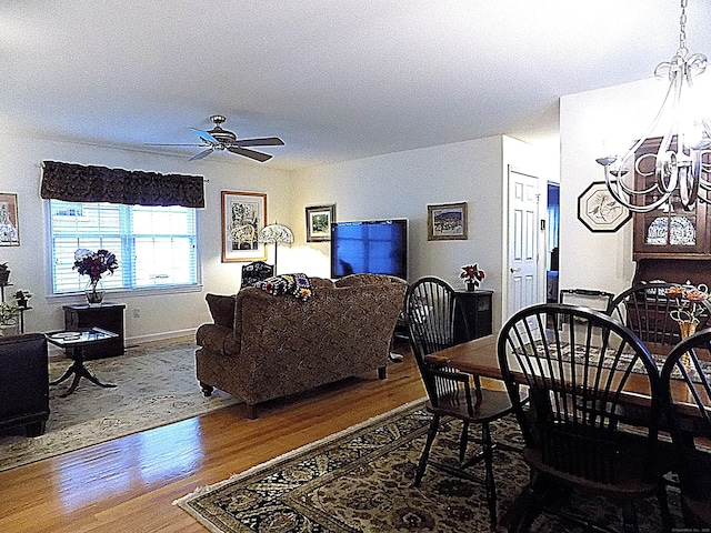 dining area with ceiling fan with notable chandelier and hardwood / wood-style flooring