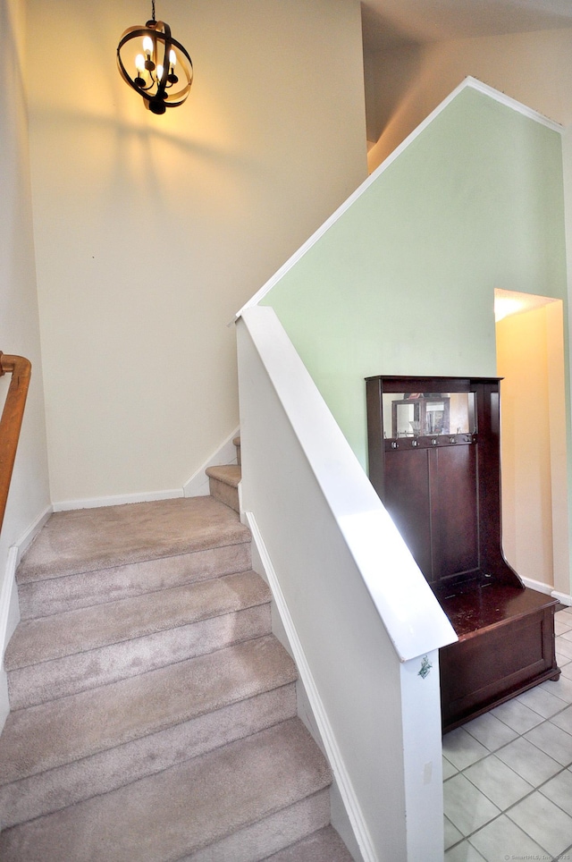 staircase featuring baseboards, tile patterned floors, and a notable chandelier