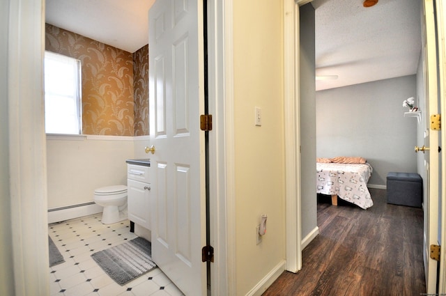 bathroom featuring a baseboard radiator, baseboards, toilet, and wallpapered walls