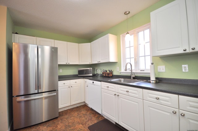 kitchen featuring white cabinetry, appliances with stainless steel finishes, decorative light fixtures, and sink