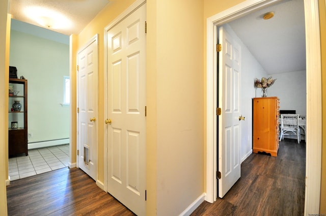 hallway featuring a baseboard radiator, baseboards, and dark wood-type flooring