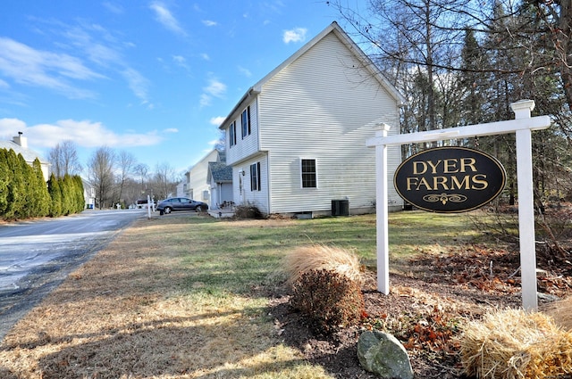 view of side of property featuring central air condition unit, driveway, and a lawn