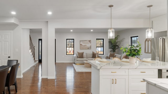 kitchen with dark wood-type flooring, decorative light fixtures, a center island, light stone countertops, and white cabinets