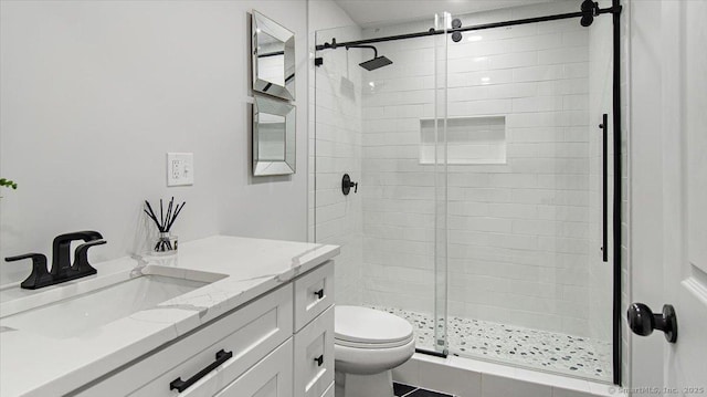 bathroom with a shower with door, vanity, and toilet