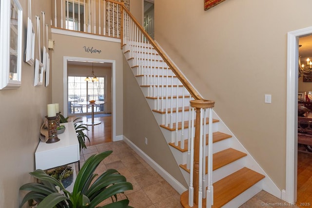 staircase with tile patterned flooring, a notable chandelier, and a high ceiling