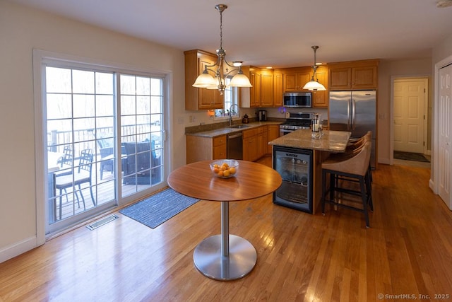 kitchen with wine cooler, decorative light fixtures, stainless steel appliances, visible vents, and a kitchen island