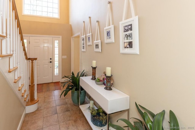 foyer entrance featuring light tile patterned floors, a high ceiling, and stairway