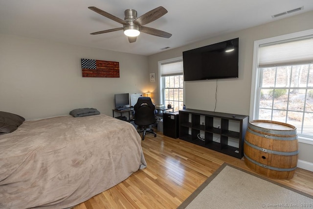 bedroom with a ceiling fan, visible vents, and wood finished floors