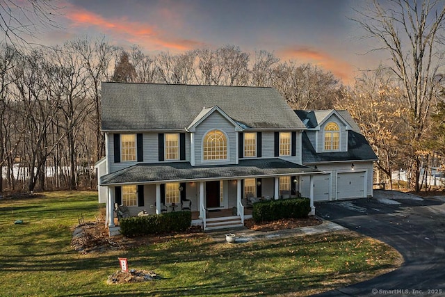 view of front of house featuring aphalt driveway, a front yard, covered porch, and a garage