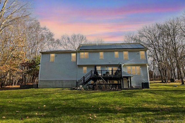 back of property at dusk with stairs, a yard, a deck, and central AC unit