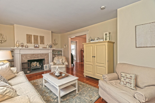 living room with dark wood-type flooring and a stone fireplace