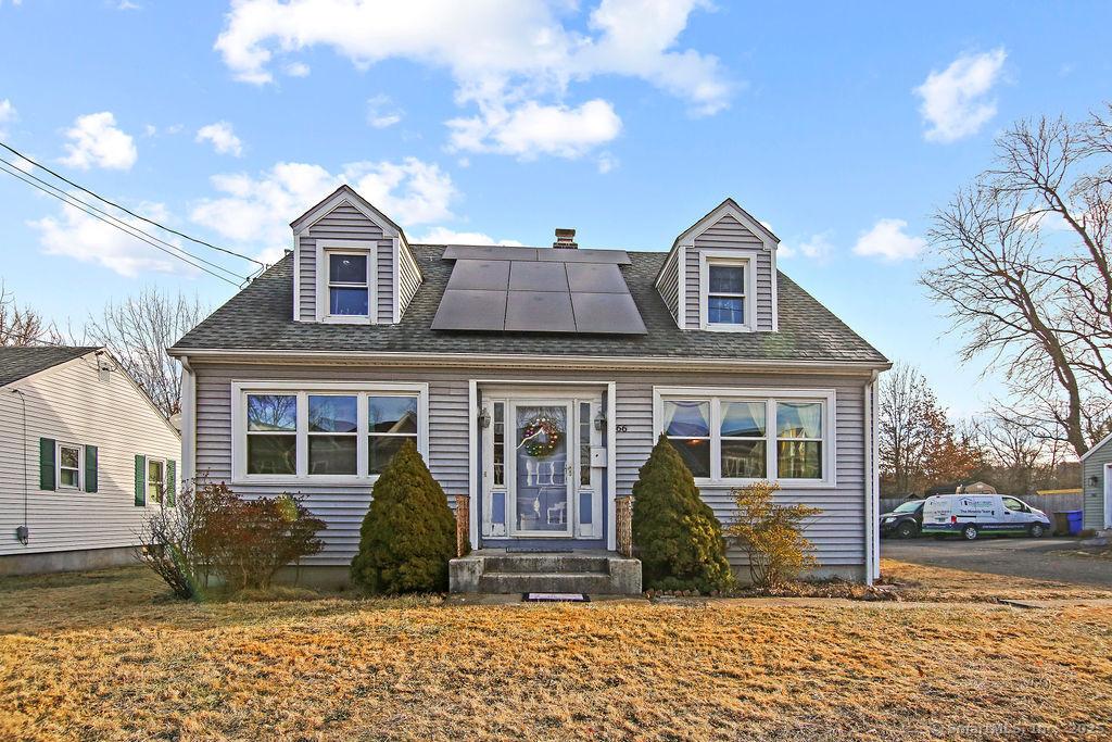 cape cod house with a front yard and solar panels