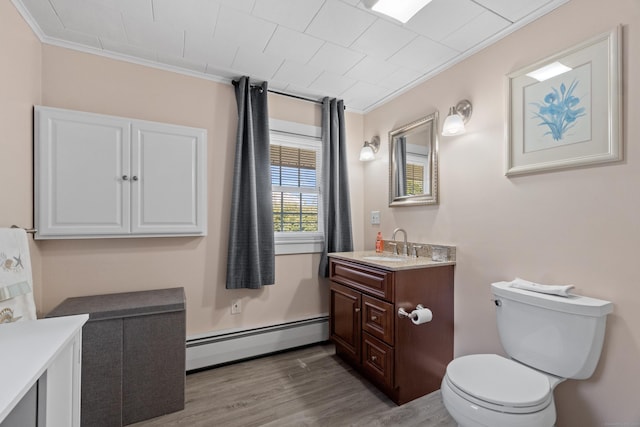 bathroom featuring crown molding, toilet, baseboard heating, vanity, and wood finished floors