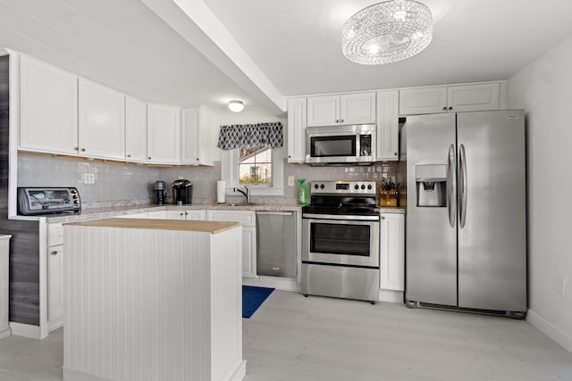 kitchen featuring appliances with stainless steel finishes, a sink, white cabinets, and decorative backsplash