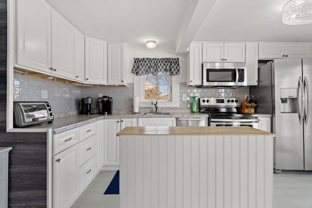 kitchen featuring white cabinets, light wood finished floors, stainless steel appliances, and a sink