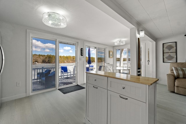 kitchen featuring baseboards, white cabinetry, wooden counters, and light wood finished floors