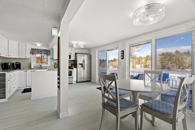 dining space featuring light wood-type flooring and an inviting chandelier