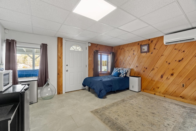 bedroom featuring a drop ceiling, a wall unit AC, and wooden walls