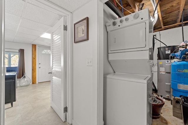 washroom featuring laundry area, hybrid water heater, and stacked washer / drying machine