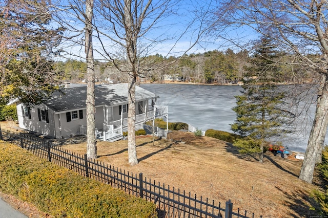 ranch-style house featuring a porch, a water view, fence, and a shingled roof