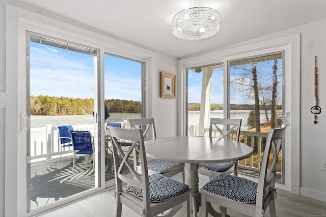 dining area featuring a water view, a notable chandelier, and wood finished floors