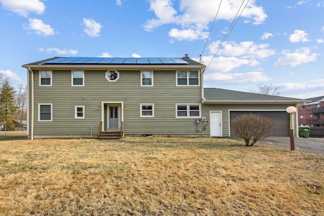 colonial-style house featuring a front yard, solar panels, and a garage