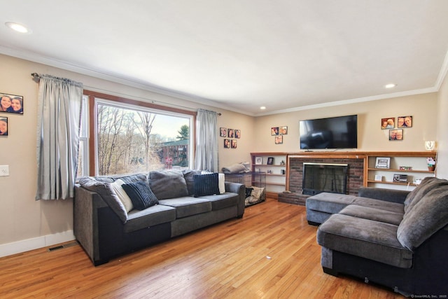 living room featuring a brick fireplace, ornamental molding, and light hardwood / wood-style flooring