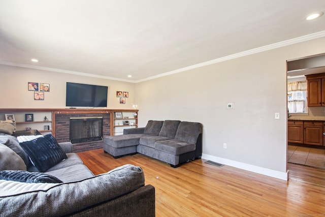 living room with a brick fireplace, crown molding, and light hardwood / wood-style flooring