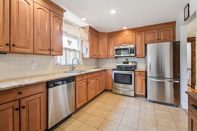 kitchen featuring tasteful backsplash, light stone countertops, sink, and stainless steel appliances