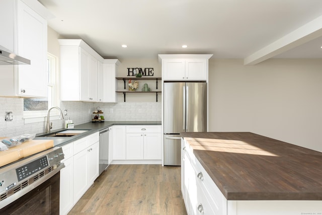 kitchen featuring appliances with stainless steel finishes, white cabinetry, sink, wooden counters, and decorative backsplash