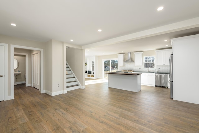 kitchen featuring sink, white cabinetry, stainless steel appliances, a center island, and wall chimney exhaust hood