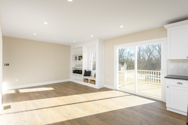 unfurnished living room featuring wood-type flooring and built in features