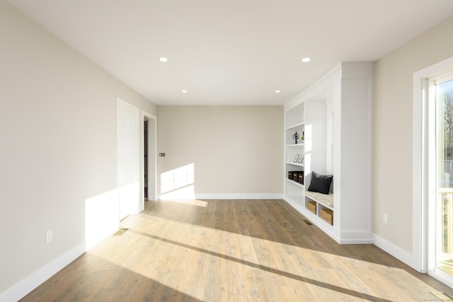 unfurnished living room featuring light wood-type flooring and built in shelves