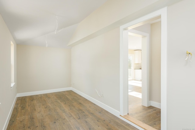 spare room featuring lofted ceiling and wood-type flooring