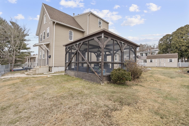 back of house with a yard, a sunroom, and a storage shed