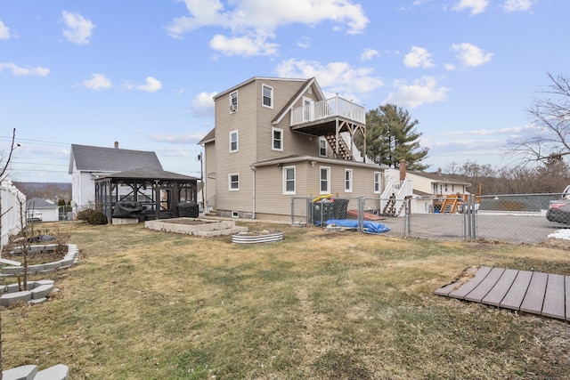 rear view of house with a wooden deck, a gazebo, and a yard