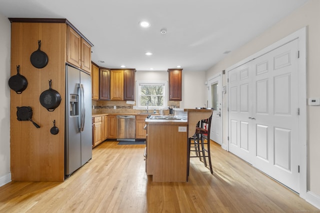 kitchen featuring light hardwood / wood-style floors, a breakfast bar area, stainless steel appliances, a kitchen island, and sink