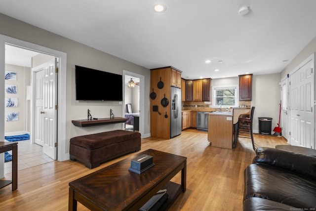 living room featuring light wood-type flooring, ceiling fan, and sink