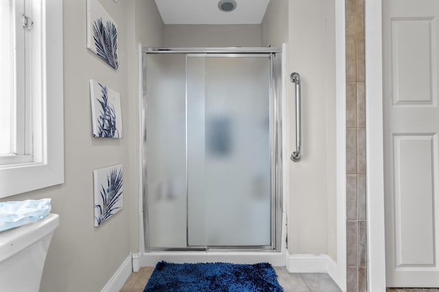 bathroom featuring toilet, tile patterned flooring, and a shower with door