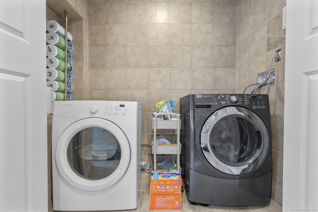 laundry room with washer and clothes dryer and tile walls