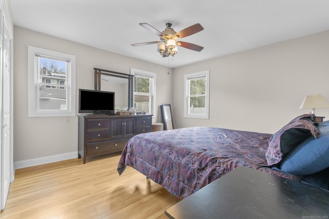 bedroom with light wood-type flooring, ceiling fan, and multiple windows