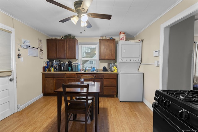 kitchen with ceiling fan, crown molding, black range with gas cooktop, light hardwood / wood-style flooring, and stacked washer / dryer