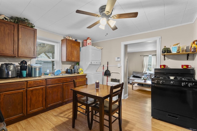 kitchen featuring sink, stacked washer / dryer, black gas range oven, and light hardwood / wood-style flooring