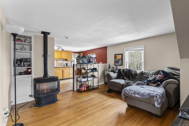 living room featuring a wood stove, light hardwood / wood-style flooring, and sink