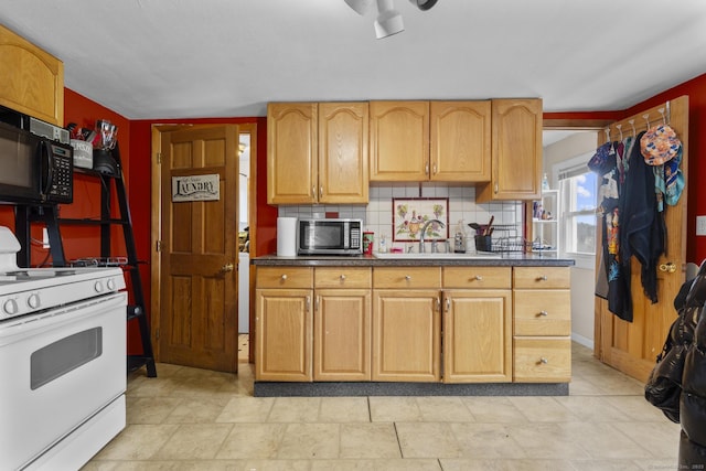 kitchen featuring backsplash, white gas range oven, and sink